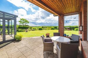 une terrasse avec une table et des chaises blanches dans l'établissement Huus Binnensee - Ferienwohnung EG - Neue Tiefe, Fehmarn, à Fehmarn