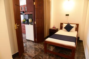 a small bedroom with a bed and a kitchen at The Kingfisher Hikkaduwa in Hikkaduwa