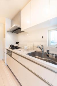 a kitchen with white cabinets and a sink at 夢の宿 東中野 134t in Tokyo