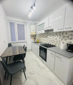 a kitchen with white cabinets and a table with chairs at DACAFI Luxury Apartment in Hunedoara