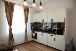 a kitchen with white cabinets and a stove top oven at Apartament DVR Baile Felix in Sînmartin