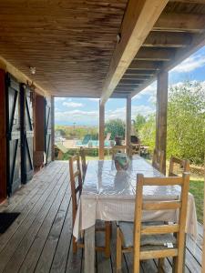 einen Holztisch mit Stühlen auf einer Holzterrasse in der Unterkunft Cottage atypique avec piscine & accès au lac 6 personnes in Molleville