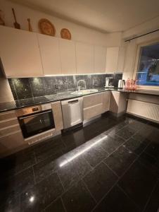 a kitchen with white cabinets and a black tile floor at Jalokivi in Lappeenranta