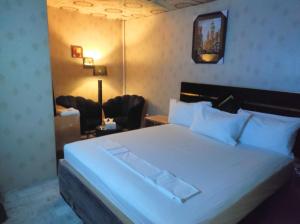 Un dormitorio con una cama blanca y una silla. en Frank-inn Guest House Islamabad, en Islamabad