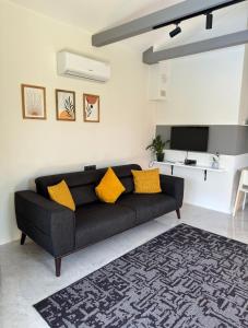 a black couch in a living room with yellow pillows at Casa Itkı in Ortaca