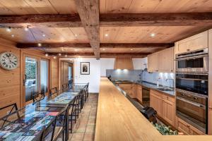 a kitchen with wooden cabinets and a long bar with stools at Ride Inn Verbier - B&B - private room and ensuite bathroom in Verbier