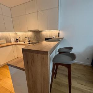 Una cocina con una encimera y dos taburetes en ella. en Lubelska SkyRes City View & Free Parking, en Rzeszów