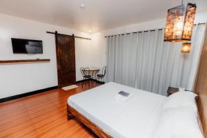 une chambre avec un lit blanc et une télévision dans l'établissement Villa Gertrudes Beach Resort, à Surigao 50 autres photos