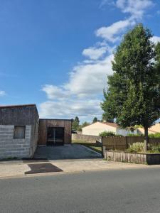 a brick building with a garage and a tree at Escapade paisible Studio design à Saint-Mesmin in Saint-Mesmin