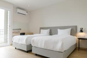 a white bedroom with a large bed with white sheets at M Hotel Kanchanaburi in Ban Chuk Kum
