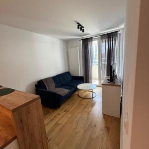 Una sala de estar con un sofá azul y una mesa. en Lubelska SkyRes City View & Free Parking, en Rzeszów
