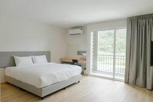 a bedroom with a bed and a large window at M Hotel Kanchanaburi in Ban Chuk Kum