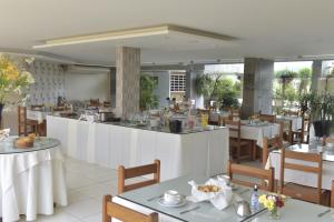 a restaurant with white tables and chairs and a counter at Panorama Hotel in Juazeiro do Norte