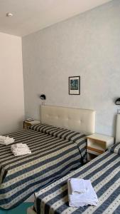 two beds in a hotel room with towels on them at Hotel Poker in Misano Adriatico