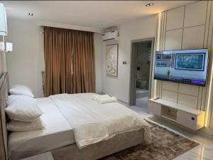 a bedroom with a large bed and a flat screen tv at Cozy three bedroom in VI with pool in Lagos