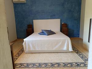 una camera con un letto bianco e una parete blu di Dimora del Sole Salento a Taurisano Altre 22 foto
