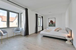 a bedroom with a bed and two chairs and windows at Spacious terraced house, center of Knokke in Knokke-Heist