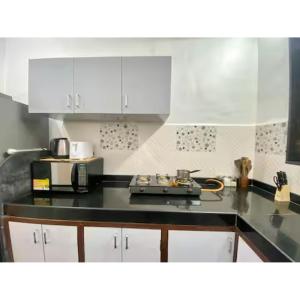 eine Küche mit weißen Schränken und einer schwarzen Arbeitsplatte in der Unterkunft African Sojourn 1 bed 2 bath Spacious Prkg Dominos 2 in Jāmb