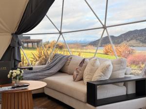 a living room with a couch and a large window at Glamping Dome - Rosé in Cromwell