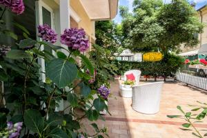 un patio con flores púrpuras y una silla blanca en Residence Villa Ofelia, en Rímini