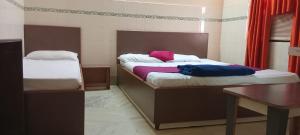 a bedroom with two beds and a table and a desk at Hotel Blue Moon Old Station Bhubaneswar in Jāmb