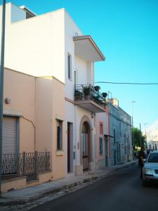 a street with a white building and a car at Le Panare Home in Spongano