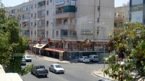 a city street with cars parked in front of a building at Destalo Court Larnaca Apartment in Larnaka