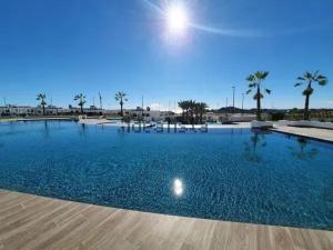 a large swimming pool with blue water and palm trees at SUNNY home in Finestrat