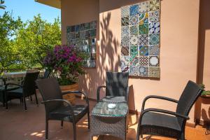 a patio with chairs and tables and mosaic tiles on a wall at Hotel Villa Degli Aranci in Maratea
