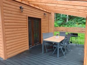a wooden deck with a table and chairs on it at Domek nad Jeziorem 5 in Kamienica Królewska