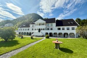 a large white building with a table in the grass at Tørvis Hotell in Luster