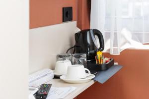 a counter with a coffee maker and cups on it at Hotel Ma Belle in Prishtinë