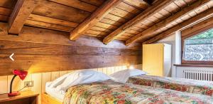 a bedroom with a bed and a wooden wall at Casa Martini in Mezzana