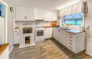 a kitchen with white cabinets and a wooden floor at 3 Bedroom Amazing Home In Sjötofta in Sjötofta