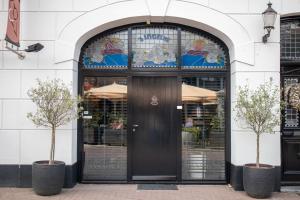 Una puerta a una tienda con dos árboles al frente. en Het Maashuys, en Arcen