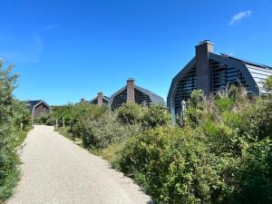 a gravel path next to two buildings on a clear day at Villa Harry aan Zee in Egmond aan den Hoef