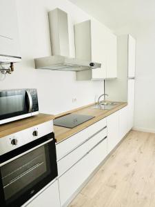 een keuken met witte kasten, een spoelbak en een magnetron bij Verga - Dietro Piazza Mazzini - Immobil Relax in Lido di Jesolo