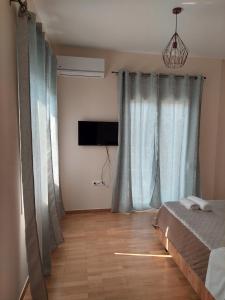 a bedroom with blue curtains and a bed and a television at Natasa's Appartment in Kalamata in Kalamata +1 photo