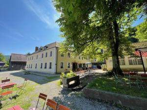 a large yellow building with a tree and tables and chairs at Ferienwohnung in Marienthal am Regen in Regenstauf