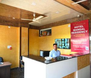 a man sitting at a counter in a restaurant at MANGAL RESIDENCY Mountain View- A Luxury Boutique Business Hotel in Bedla +33 photos
