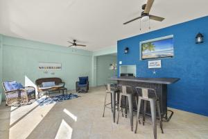a living room with a blue wall and stools at 241 Oasis Pearl- 3BR Pool Home! home in Fort Myers Beach