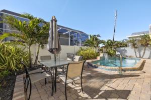 a table and chairs with an umbrella next to a pool at 241 Oasis Pearl- 3BR Pool Home! home in Fort Myers Beach