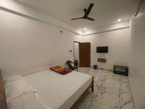 a bedroom with a bed and a ceiling fan at LunaBloom Stays in Maraiyūr