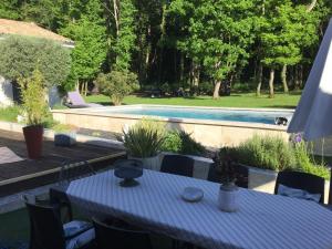 a table and chairs next to a swimming pool at Havre de paix avec 2 chambres et salle de bain in Claix