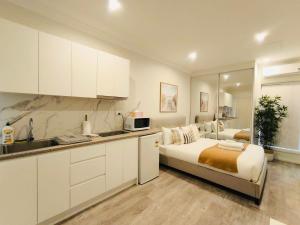 a large white kitchen with a bed and a sink at Peaceful Studio Hidden in Kingsgrove in Sydney
