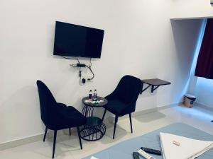 KondapurにあるJashwitha Mukkanti Homesの椅子2脚、テーブル、テレビが備わる客室です。