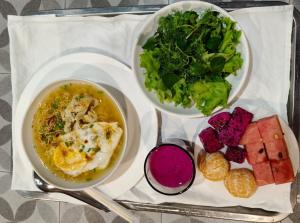a tray with two bowls of food and a plate of vegetables at Opera Premier Hotel in Luang Prabang