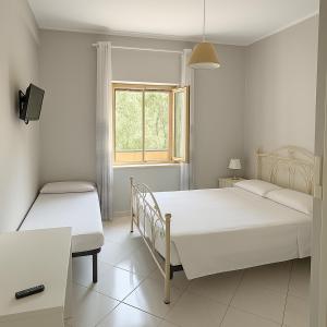a white bedroom with two beds and a window at Villa Lesina Casa Vacanze in Santa Maria di Castellabate