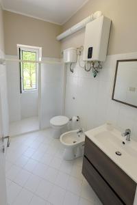 a white bathroom with a toilet and a sink at Villa Lesina Casa Vacanze in Santa Maria di Castellabate +32 photos
