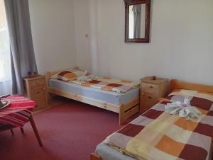 a bedroom with two beds and a mirror on the wall at Hagyományőrző és múltidéző porta in Báta